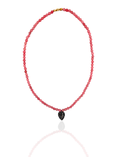 Necklace with red beads and a black heart-shaped pendant on a white background