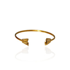 A gold open cuff bangle bracelet with textured, flower-like ends, displayed on a clean white reflective surface.