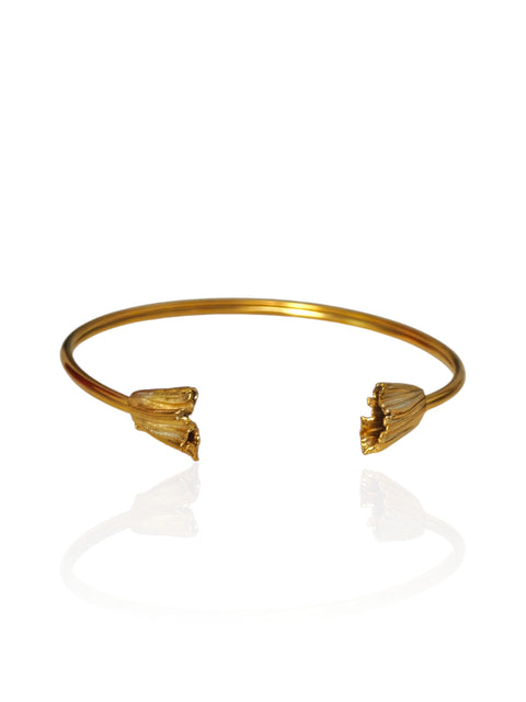 A gold open cuff bangle bracelet with textured, flower-like ends, displayed on a clean white reflective surface.