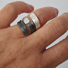 Hand wearing two silver rings on a plain background, ring by Athenart , handmade in Athens . Stackable rings