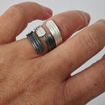 Hand wearing two silver rings on a plain background, ring by Athenart , handmade in Athens . Stackable rings