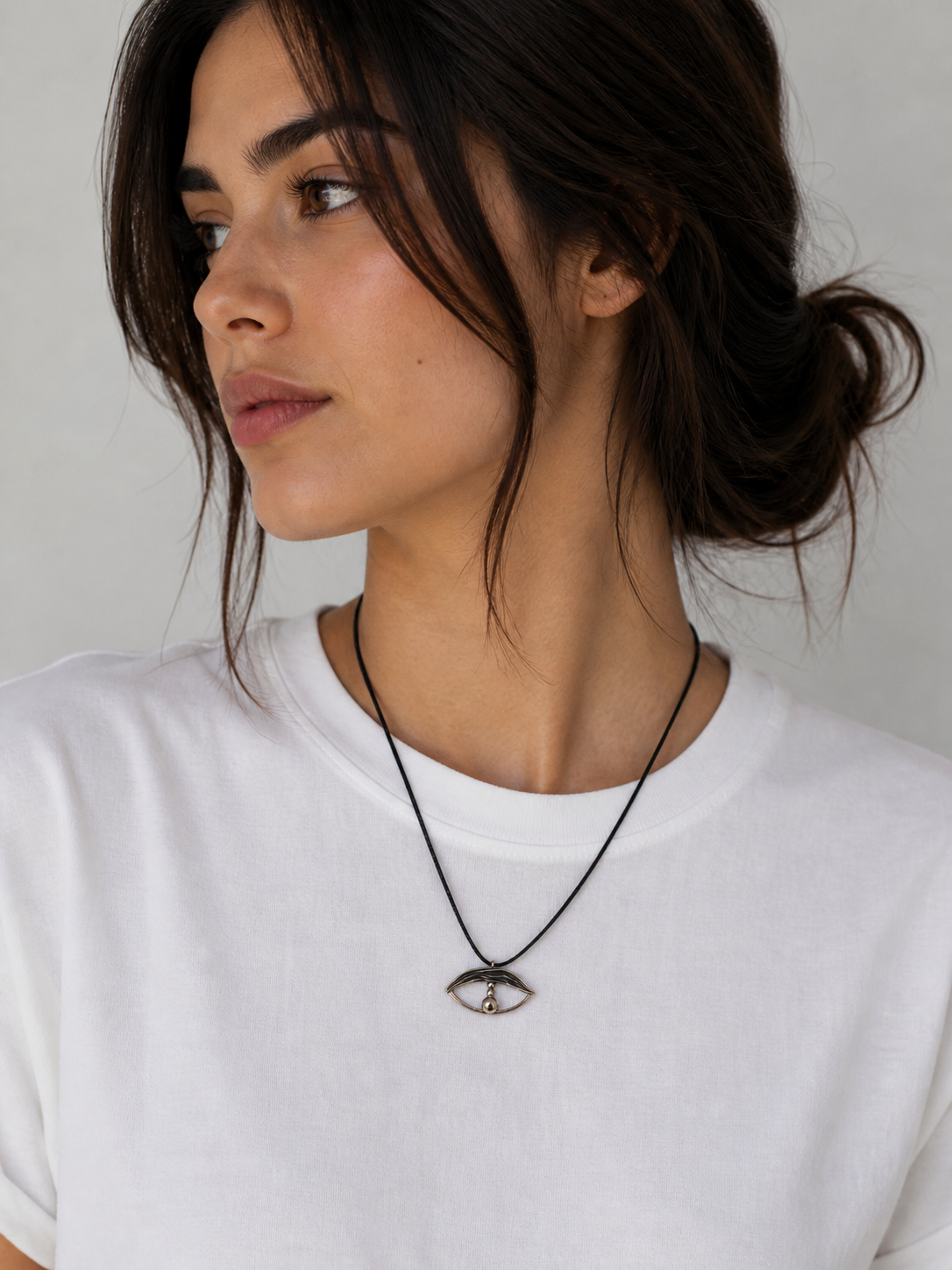 Model wearing minimal evil eye cord necklace by Athenart on white T-shirt