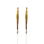 Pair of long, thin earrings with a central pearl on a white background