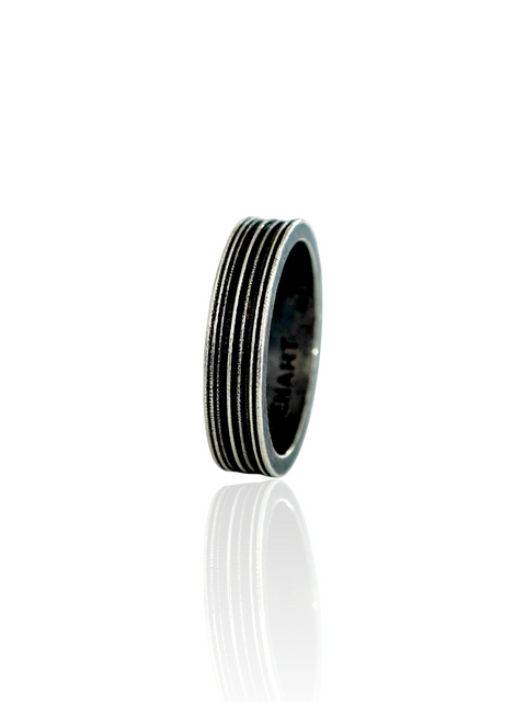 AN OXIDIZED silver-toned metal ring with a textured, ribbed exterior and a polished inner band, shown on a clean white background with a soft reflection below.