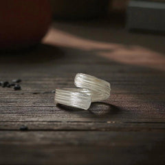 Two clear crystal rings on a wooden surface with a blurred background
