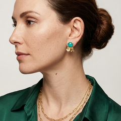 Woman wearing gold chain necklace and Chrysocolla earrings against a neutral background