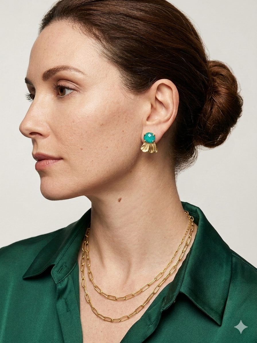 Woman wearing gold chain necklace and Chrysocolla earrings against a neutral background