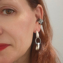 Close-up of a woman wearing silver hoop earrings with a plain background