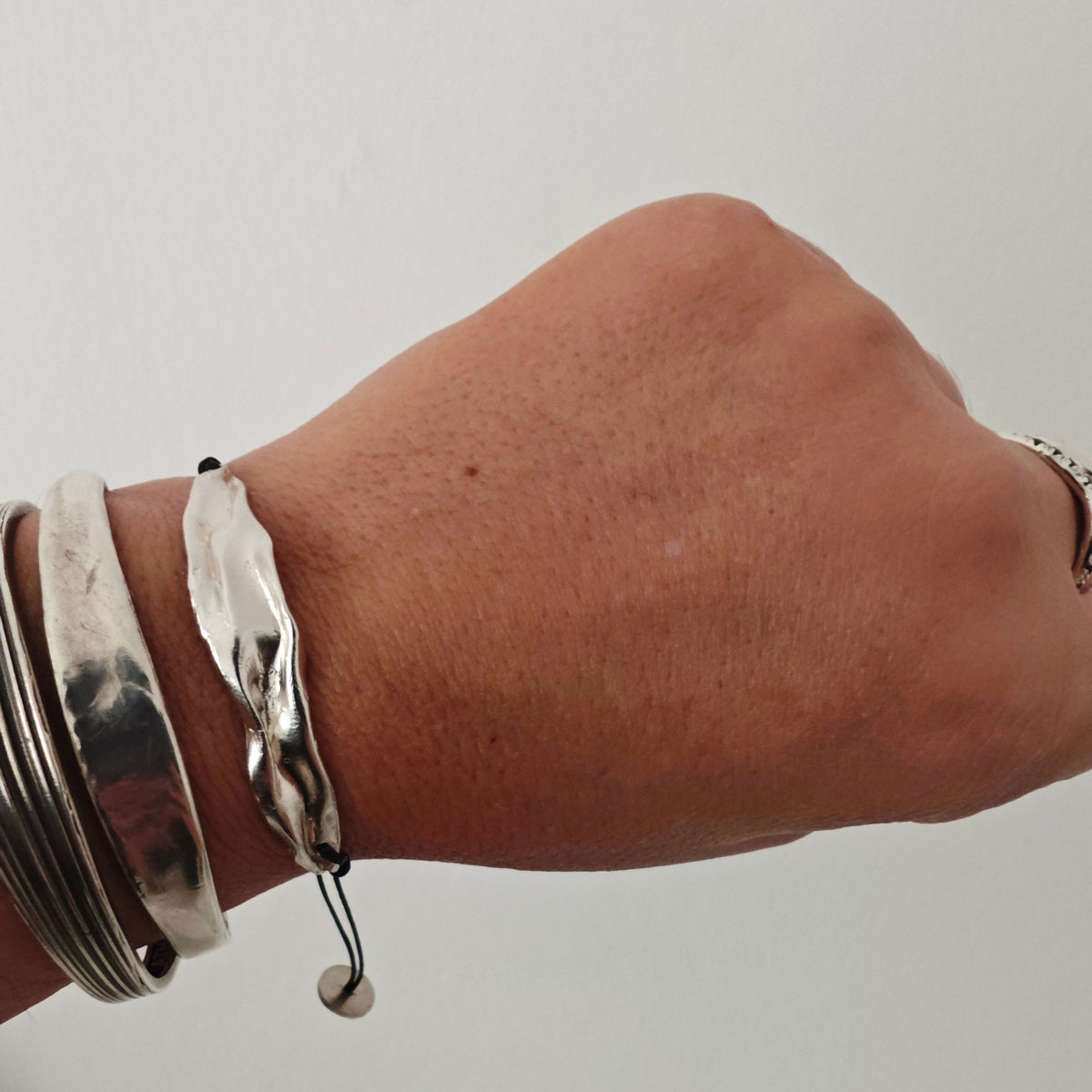 Peplos drape Bar Bracelet stacked on wrist—handmade silver bar on black cord