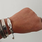 Peplos drape Bar Bracelet stacked on wrist—handmade silver bar on black cord