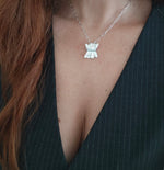 Silver necklace with a unique pendant worn by a person in a black outfit.