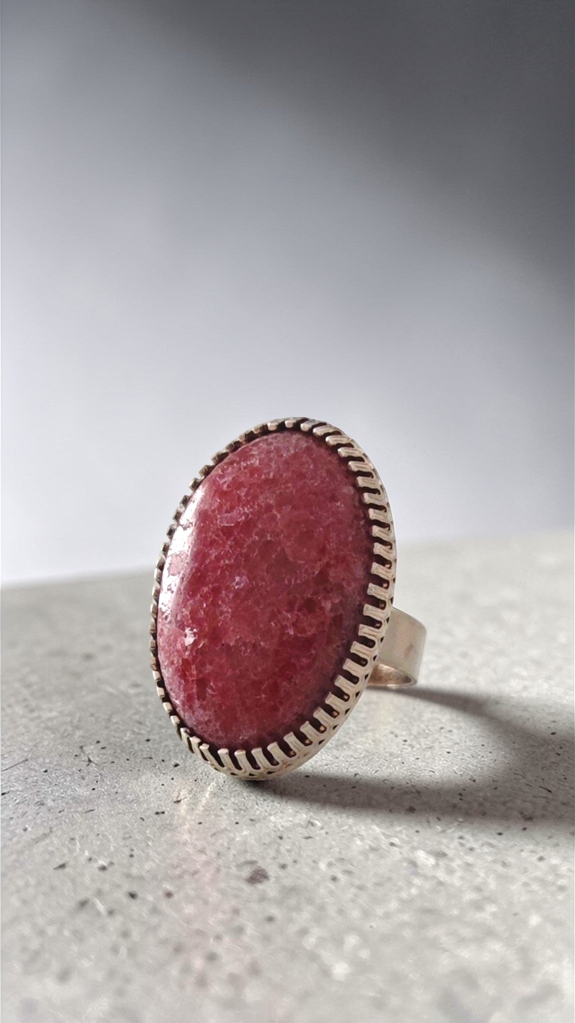 Close-up of one-of-a-kind pink rhodonite stone cabochon ring showing bezel detail and stone texture