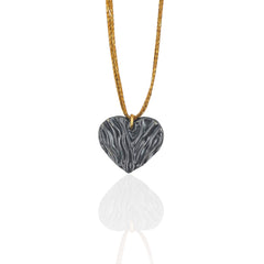 Heart-shaped pendant on a gold cord against a white background