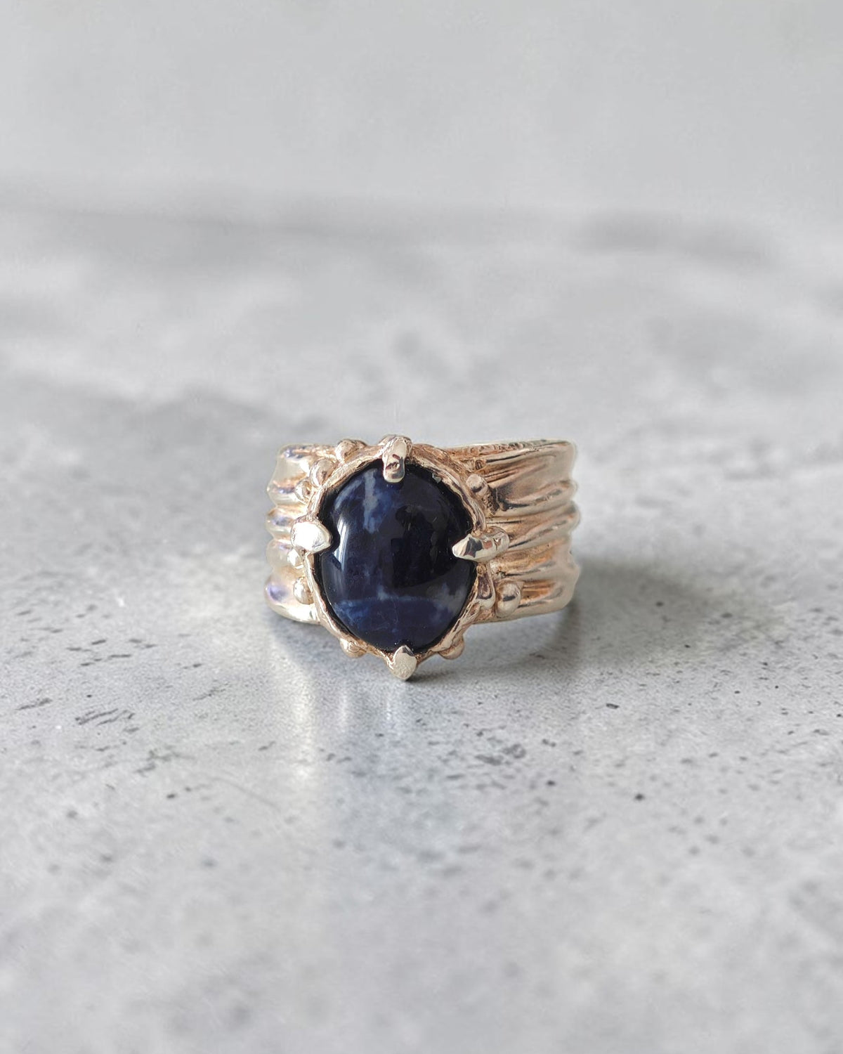 andmade sterling silver sodalite ring on grey stone surface with sculpted folds