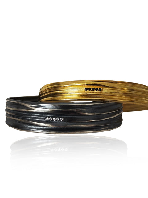 Two gold and black bracelets on a white background