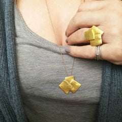 Hand wearing Athenart Bouquet Ring and matching pendant – golden sculptural jewelry.