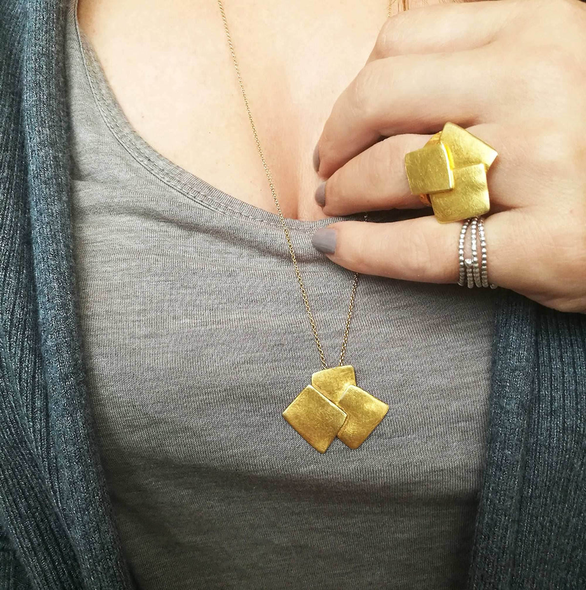 Hand wearing Athenart Bouquet Ring and matching pendant – golden sculptural jewelry.