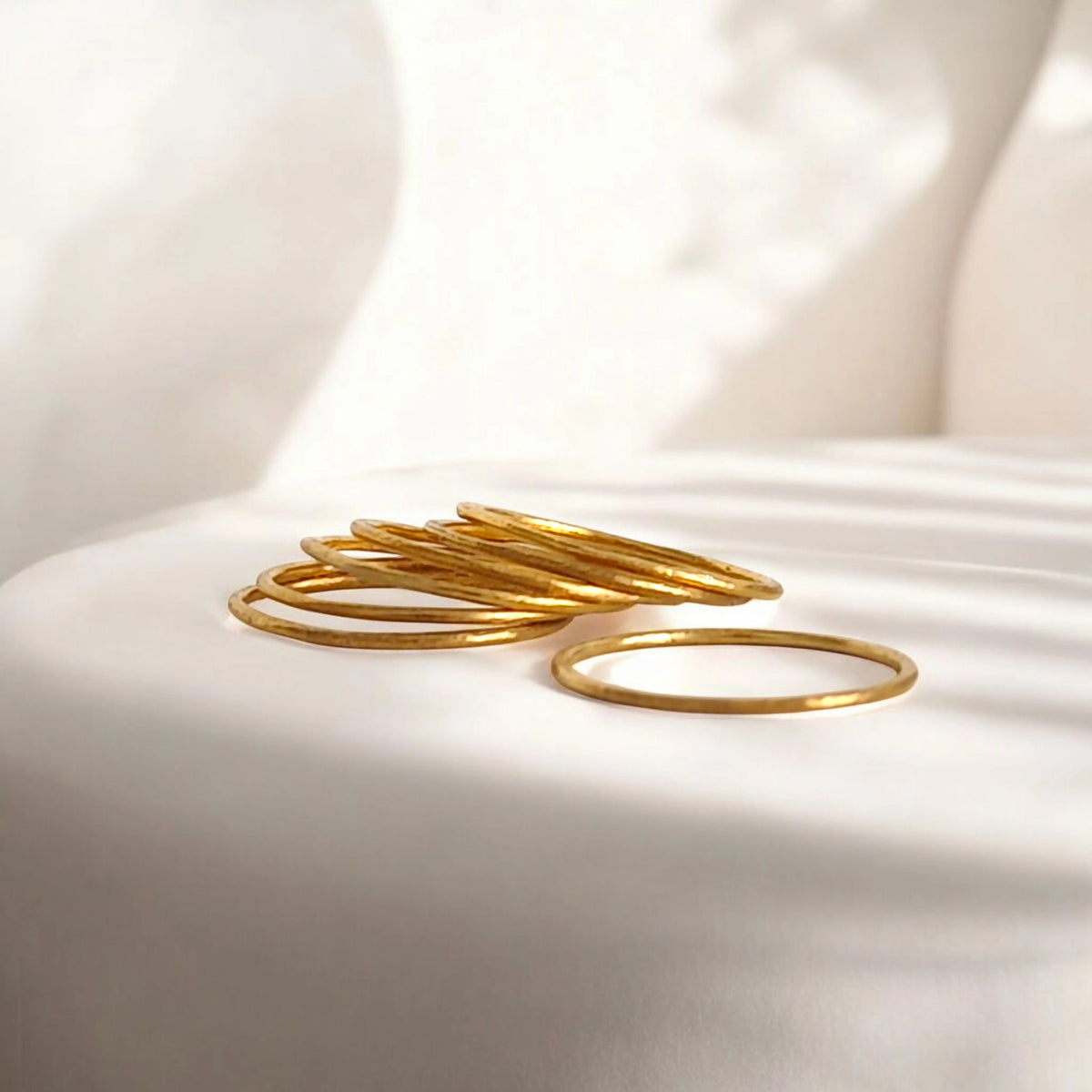 Gold bangles on a white fabric surface