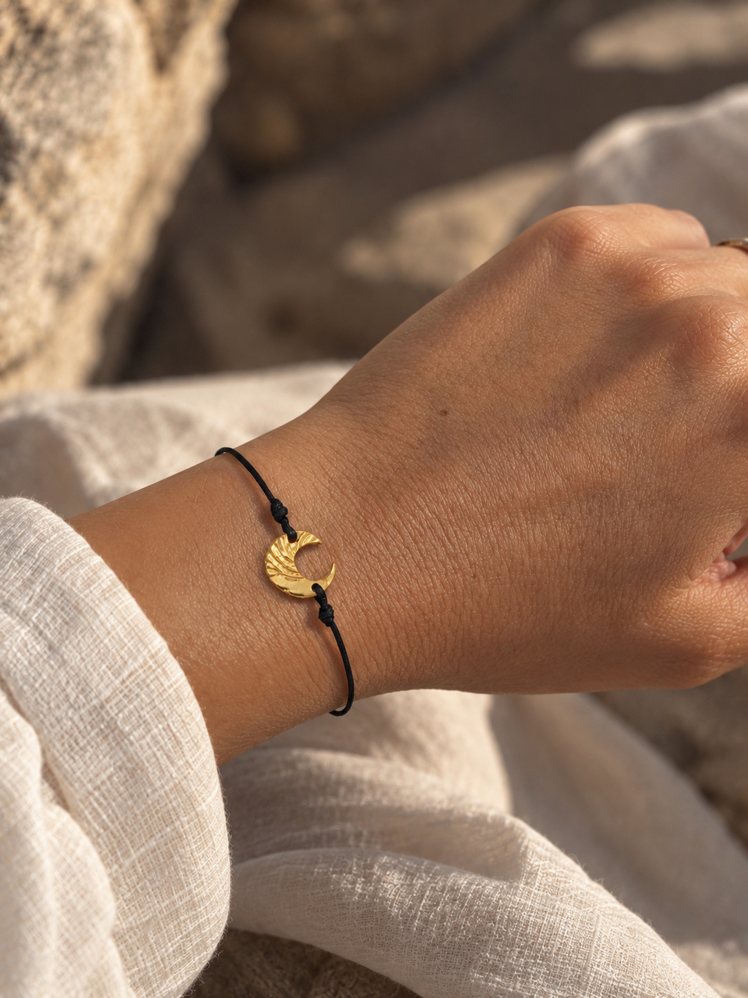 Moon Whisper gold-plated silver cord bracelet with textured crescent moon charm and adjustable closure.