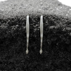 Pair of gold earrings on a textured black surface