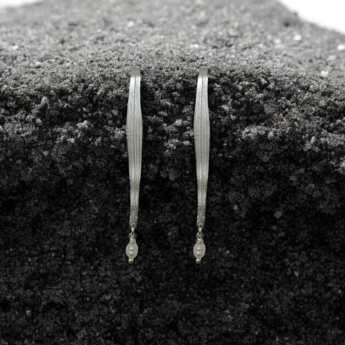 Pair of gold earrings on a textured black surface