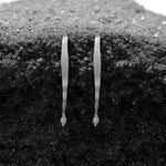 Pair of gold earrings on a textured black surface