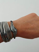 Wave bracelet worn on hand with silver rings and layered bracelets