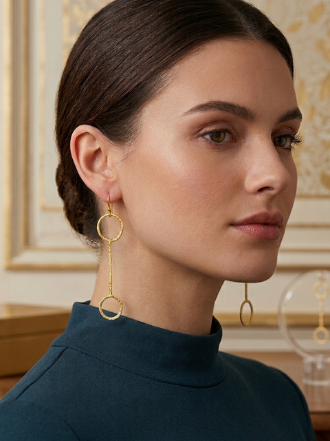 Woman wearing gold hoop earrings with a decorative background
