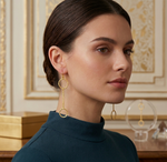 Woman wearing gold hoop earrings with a decorative background