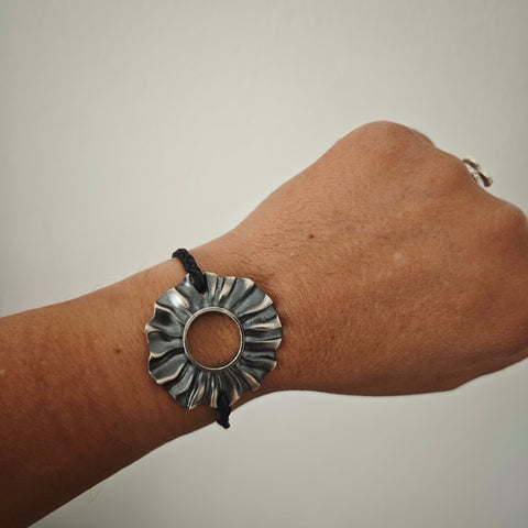 Helios oxidized silver sun bracelet (4×4 cm) with braided cord and silver toggle, studio packshot , Athenart Jewelry.”