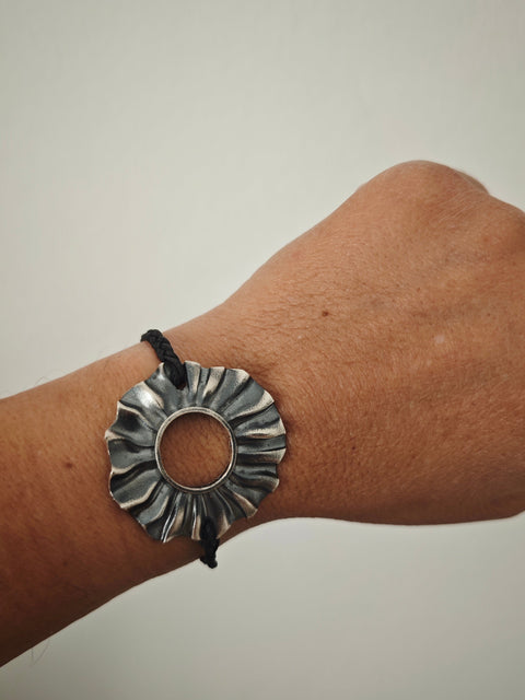 Helios oxidized silver sun bracelet (4×4 cm) with braided cord and silver toggle, studio packshot , Athenart Jewelry.”