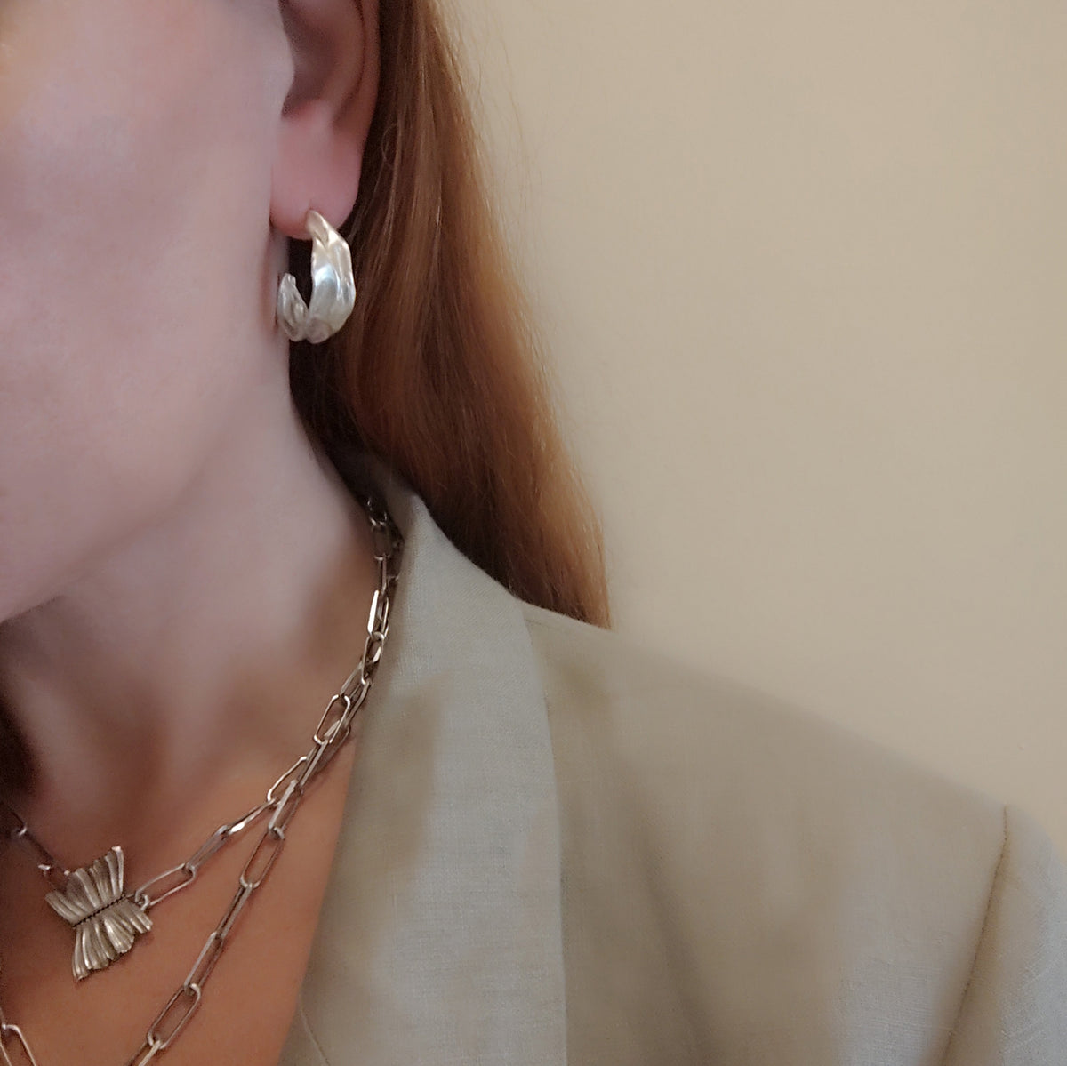 Model wearing Athenais Drapé Hoops in polished silver with layered chain and Peplos pendant, lifestyle portrait