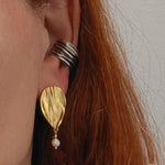 Close-up of Peplos pearl drop earring on ear, gold plated finish with oxidized ear cuff
