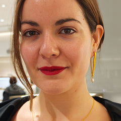 Woman wearing a gold necklace and earrings with a blurred background