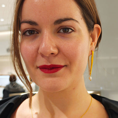 Woman wearing a gold necklace and earrings with a blurred background