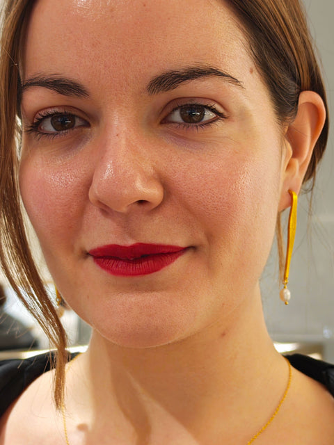 Woman wearing a gold necklace and earrings with a blurred background