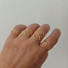 Hand wearing gold geometric ring on a plain background