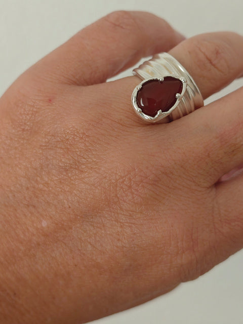 Naiás carnelian ring in sterling silver on hand, wide draped adjustable bandbackground