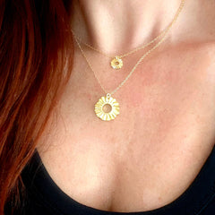 Model wearing layered Helios Guardian Sun lucky charm necklaces in gold — small 1 cm and medium 2 cm, Athenart Jewelry, handmade in Athens.