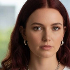 Close-up of Athenais Drapé Hoop in silver on ear, paired with chain necklace and Peplos pendant, warm light