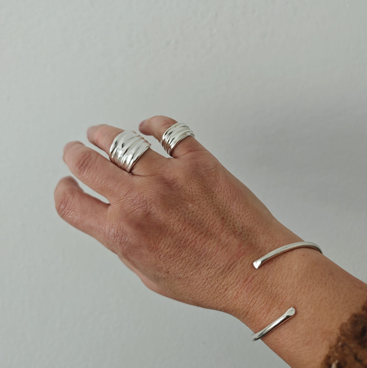 Sterling silver open cuff bracelet worn on wrist, minimalist bangle style