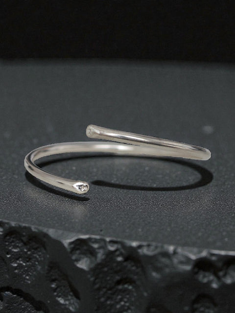 Minimal sterling silver open bangle cuff bracelet on black textured surface