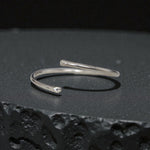 Minimal sterling silver open bangle cuff bracelet on black textured surface