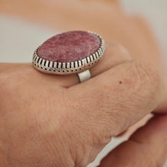 Close-up of a hand wearing a ring with a pink stone and silver band.