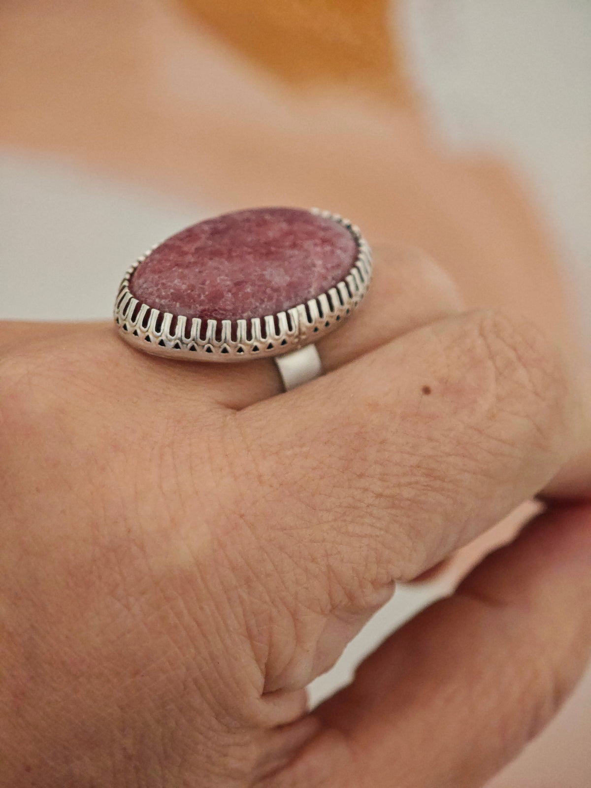 Close-up of a hand wearing a ring with a pink stone and silver band.
