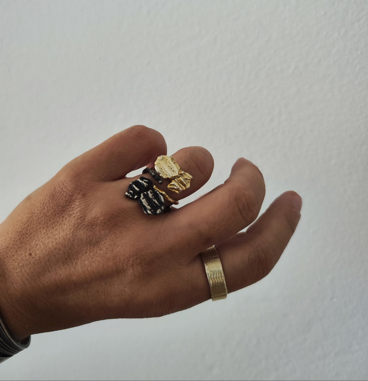 Hand wearing layered multiple gold and oxidized rings made   by Athenart in Athens