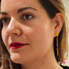 Close-up of a woman wearing gold chain earrings.
