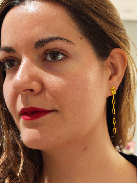 Close-up of a woman wearing gold chain earrings.