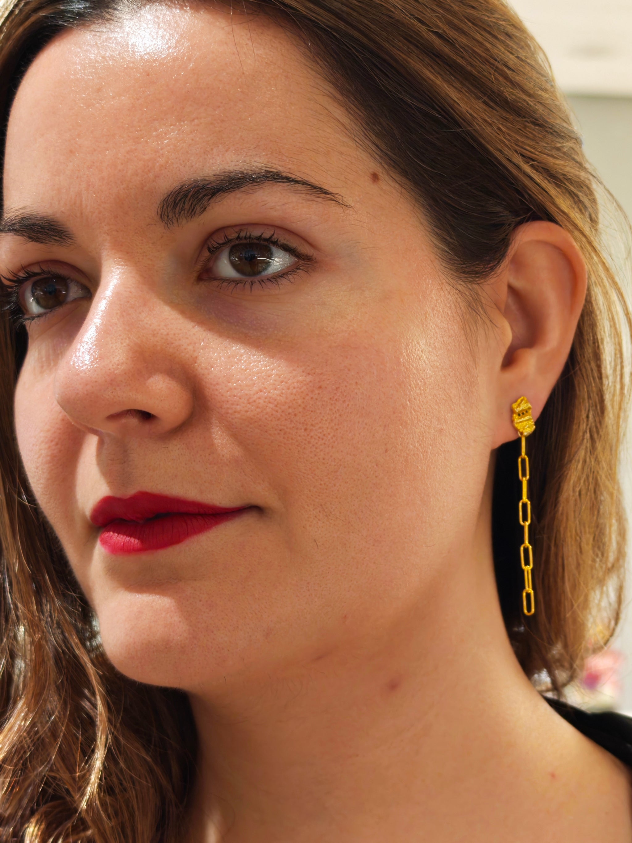 Close-up of a woman wearing gold chain earrings.