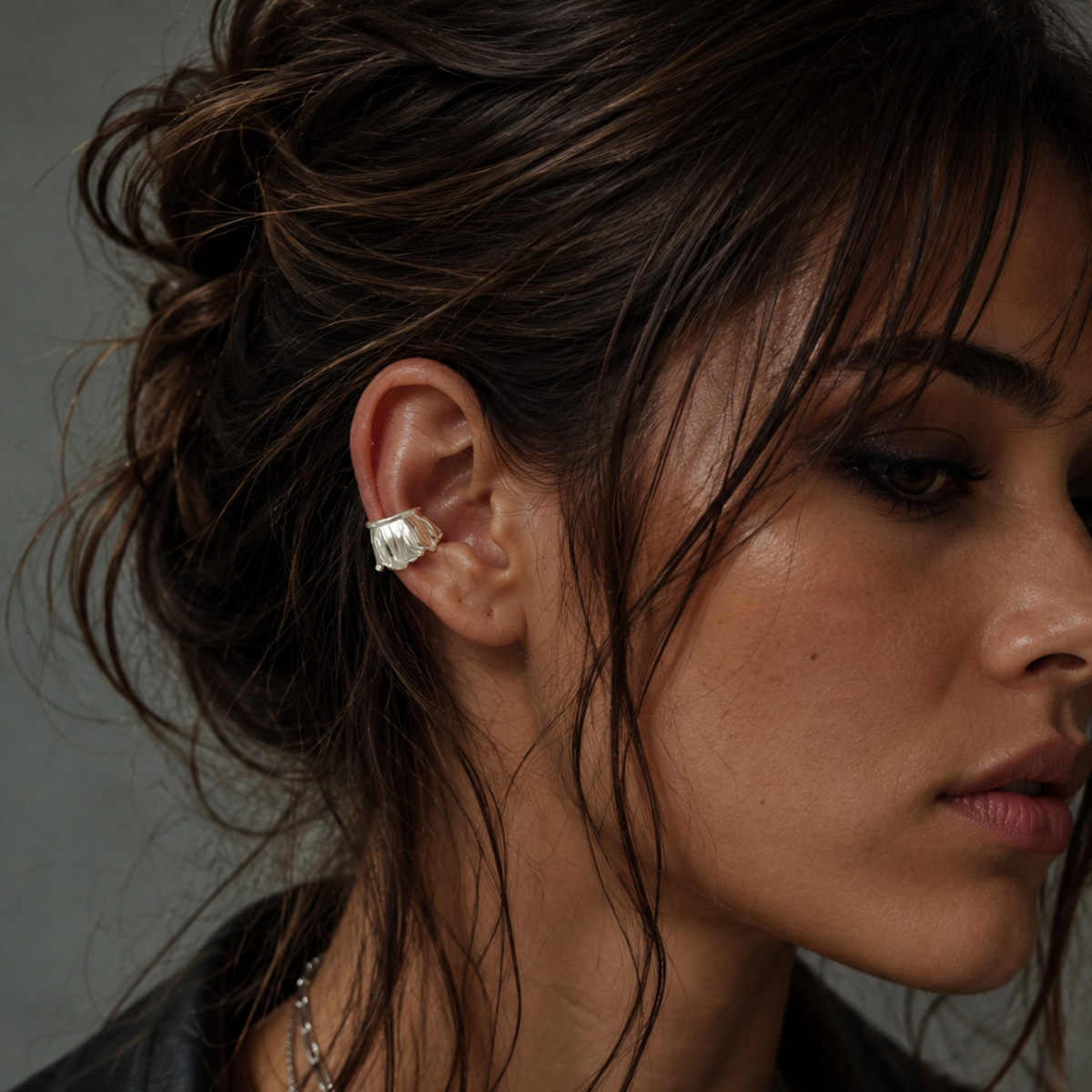 Close-up of a woman wearing a silver earring with a dark background